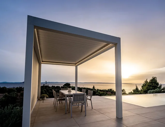 Bioclimatic pergola with modern design and LED lighting, in an outdoor space with a sea view and pool.